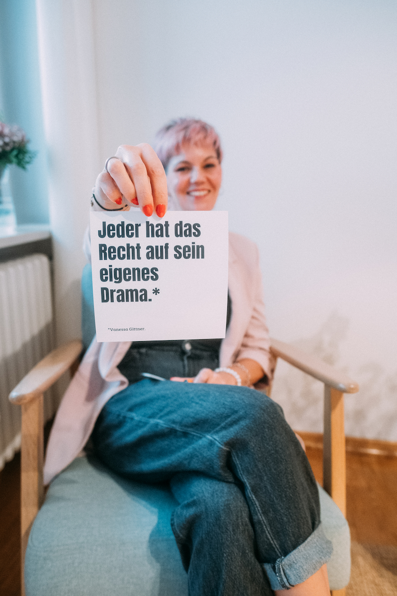 Sarah Herter hält eine Karte mit der Aufschrift „Jeder hat das Recht auf sein eigenes Drama.“